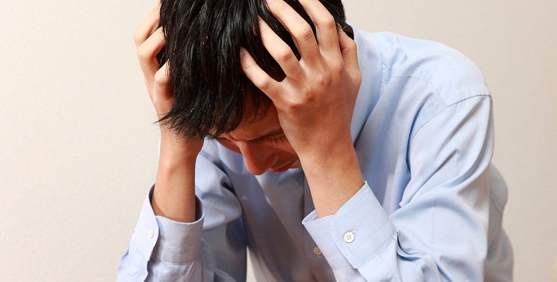 Illustrative photo of a person sitting with their hands on their head